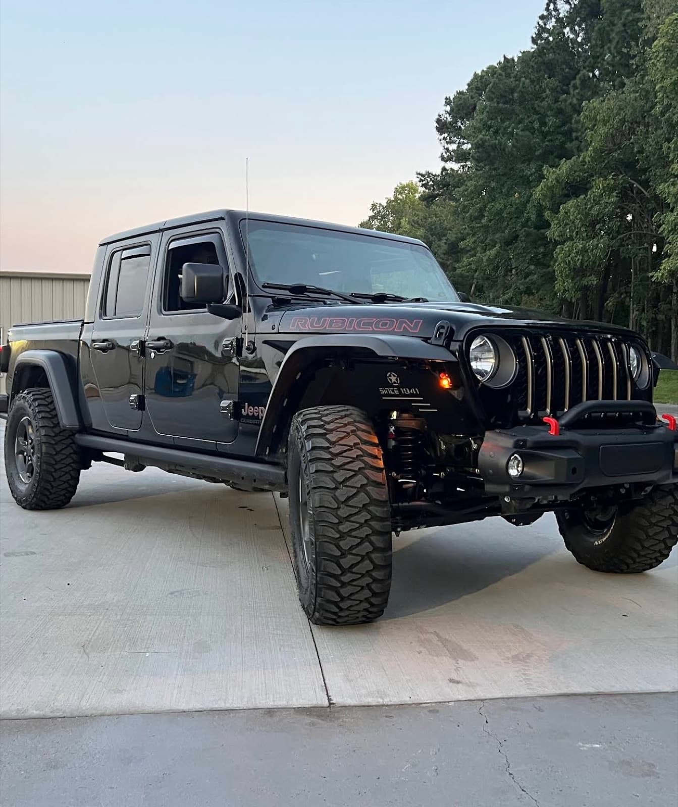 Lifted black Jeep Gladiator Rubicon on mud-terrain tires parked outside Tires To Go at dusk