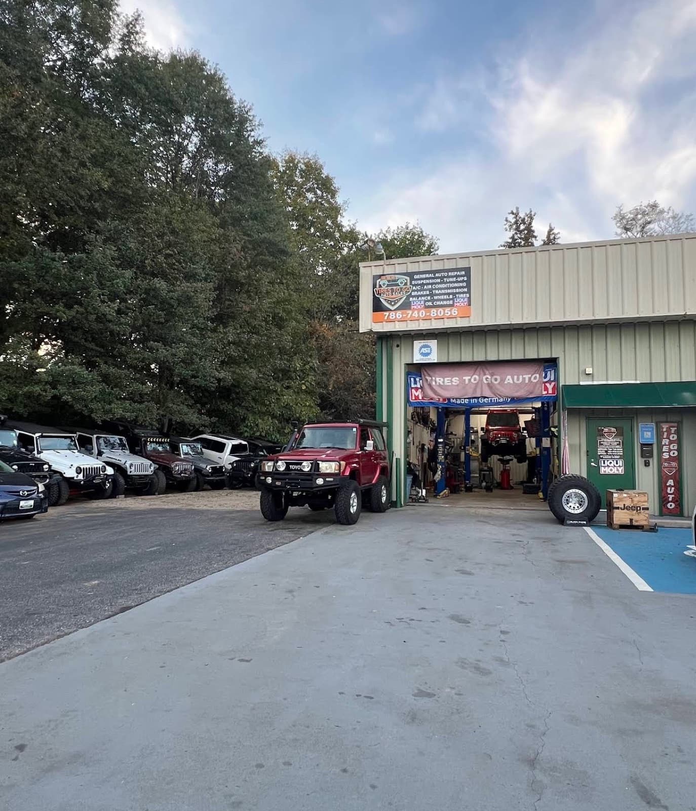 Exterior of the Tires To Go Auto shop with a row of Jeeps and an open service bay