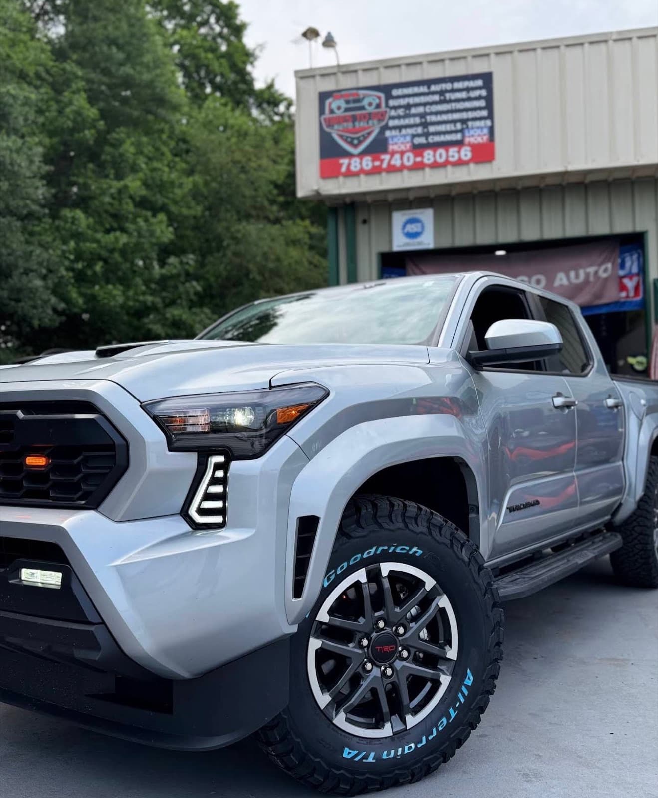 Silver Toyota Tacoma TRD on BFGoodrich all-terrain tires and TRD wheels in front of the shop